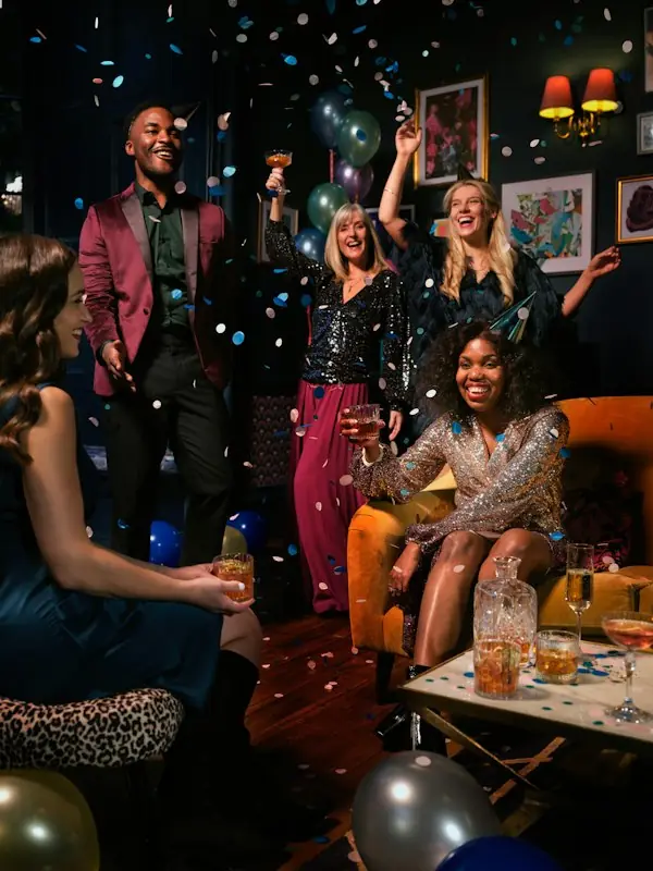 Friends celebrating under falling confetti and balloons