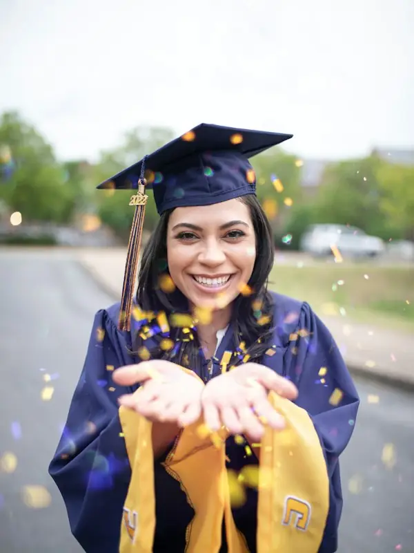 A graduate blowing confetti from her hands